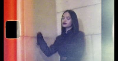 a woman standing next to a wall holding a cell phone