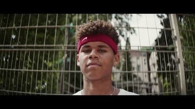 a man with a red headband standing in front of a fence