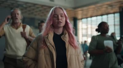 a woman with pink hair walking through a building
