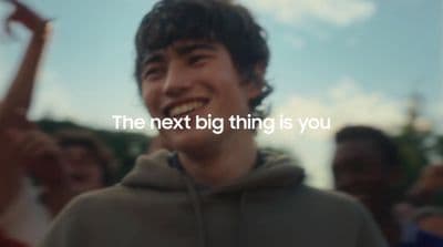 a man with a hoodie is smiling and holding a cell phone