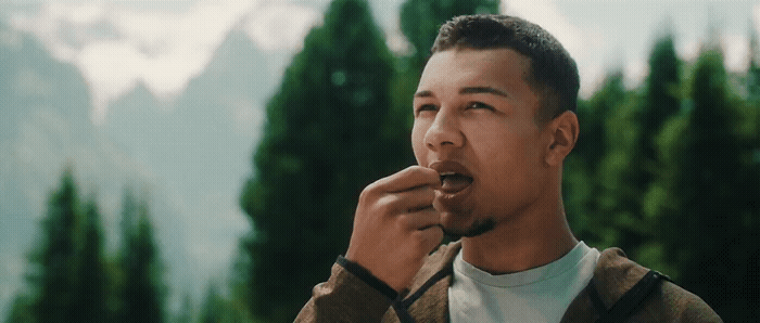 a man eating something with trees in the background