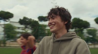 a man in a gray hoodie smiles at the camera