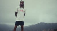 a man with long hair standing on a hill