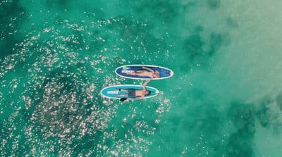 a couple of people riding on top of surfboards in the ocean