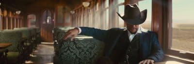 a man in a cowboy hat leaning against a window