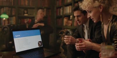 a man and a woman sitting at a table with a laptop
