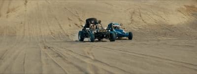 two people driving a buggy in the sand