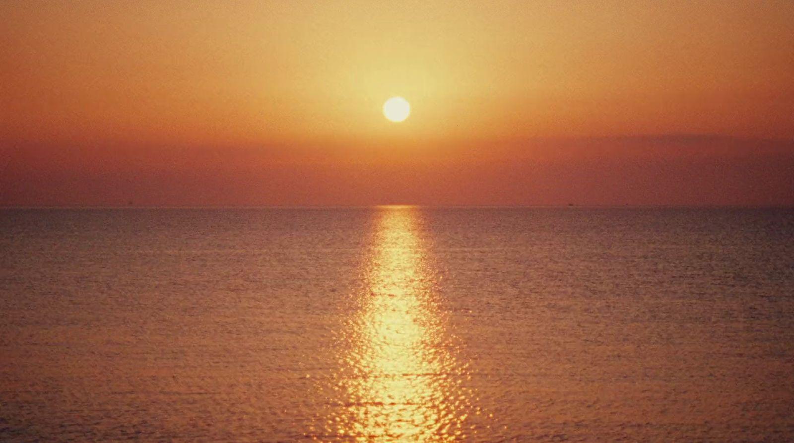 the sun is setting over the ocean on a clear day