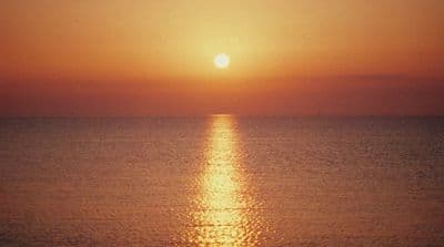 the sun is setting over the ocean on a clear day
