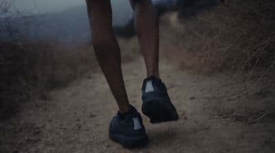 a person walking down a dirt road with their shoes on