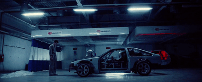 a man standing next to a car in a garage