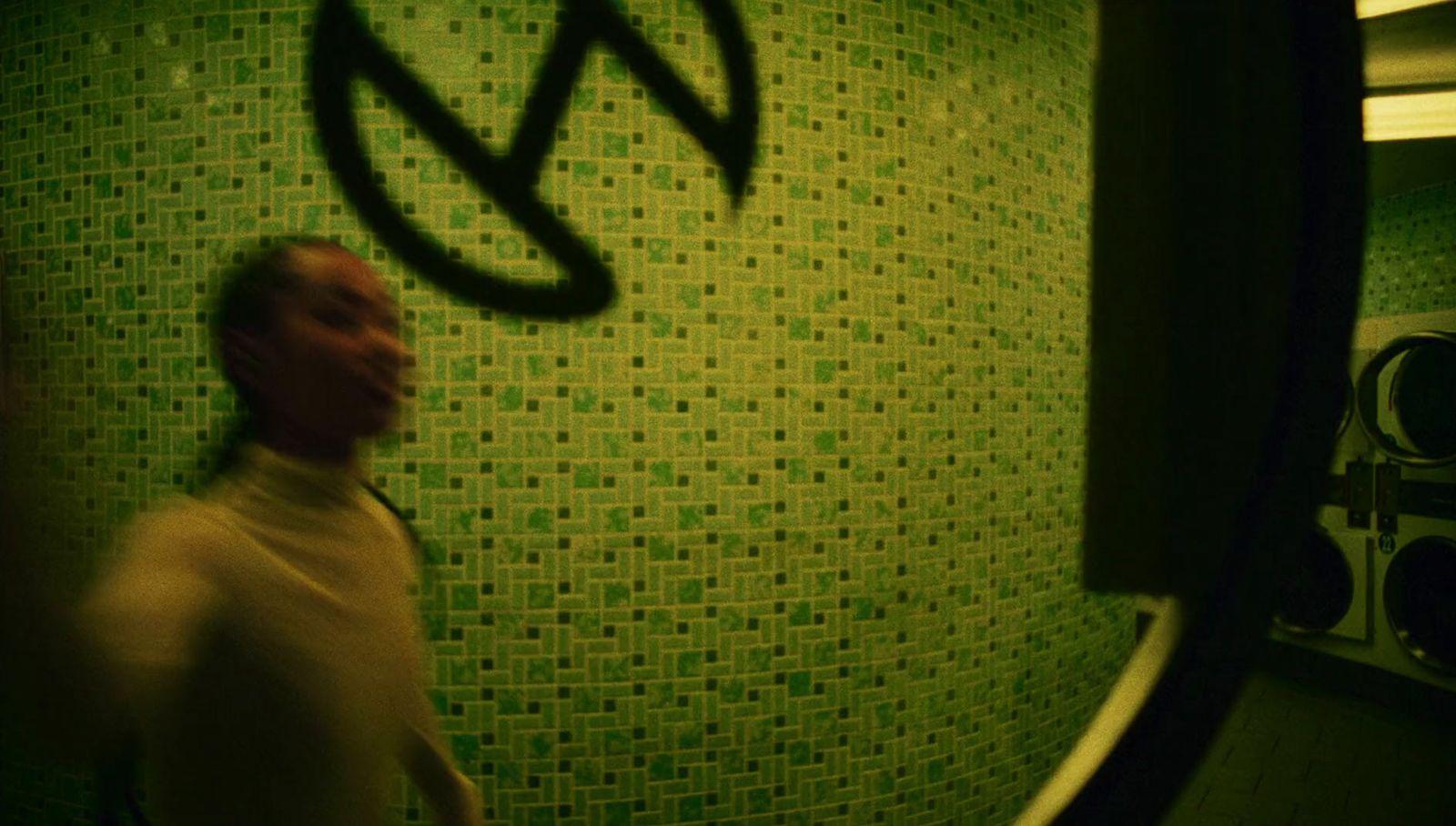 a man standing in front of a green tiled wall