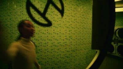a man standing in front of a green tiled wall