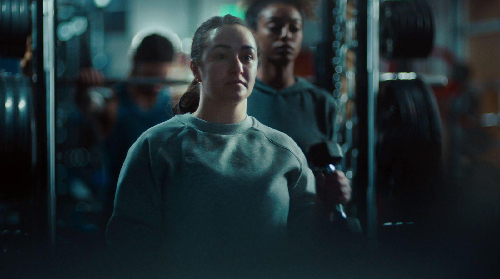 a woman standing in a gym holding a barbell