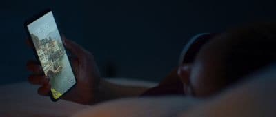a person laying in bed holding a cell phone