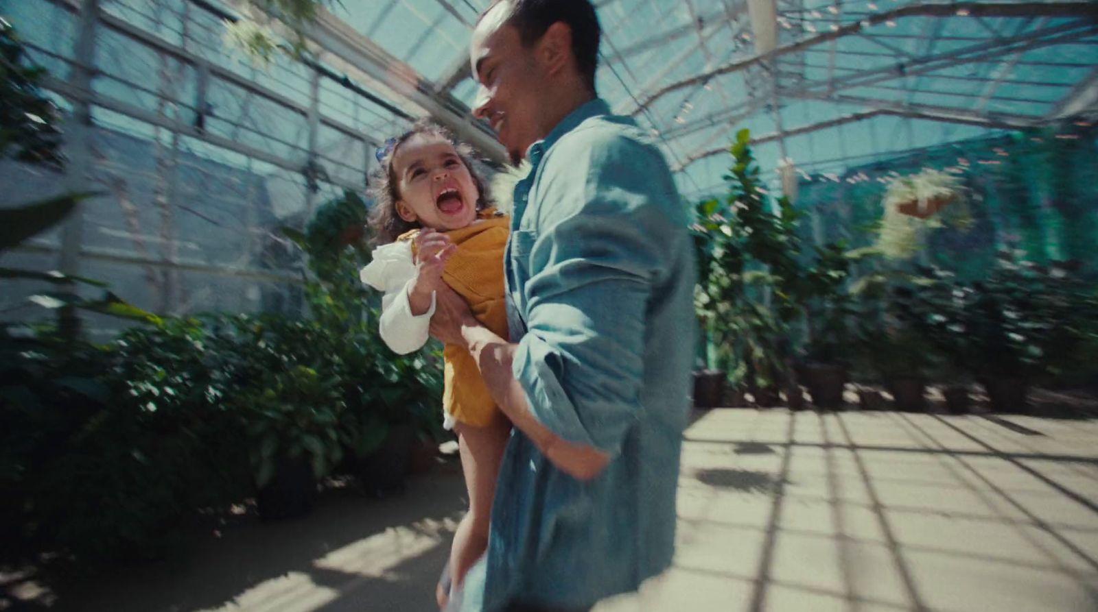 a man holding a little girl in a greenhouse