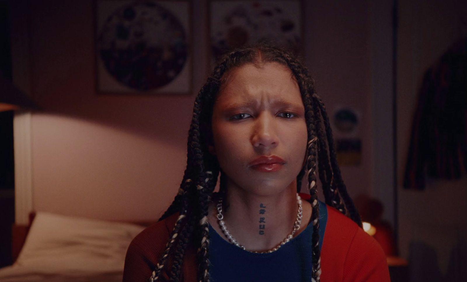 a woman with dreadlocks stares into the camera