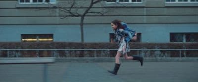 a woman with a backpack running down a sidewalk