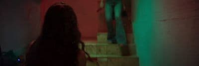 a woman with long hair walking down a set of stairs