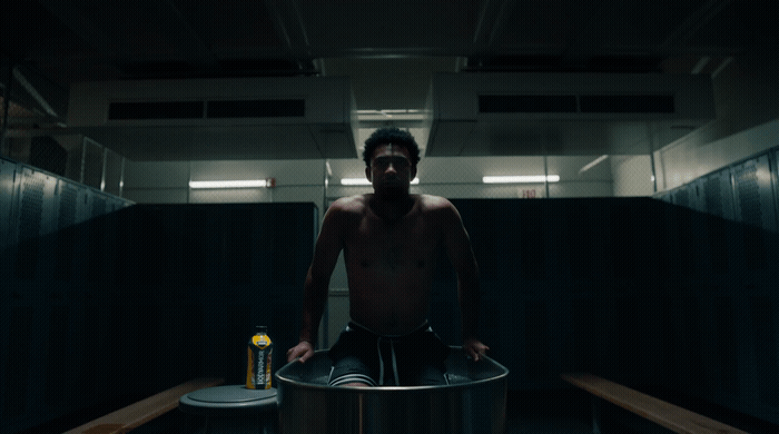 a shirtless man sitting on top of a metal barrel