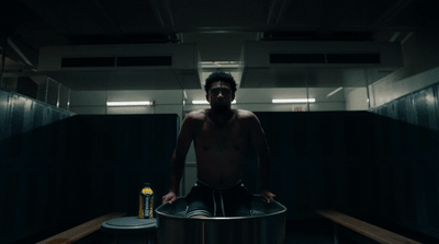 a shirtless man sitting on top of a metal barrel
