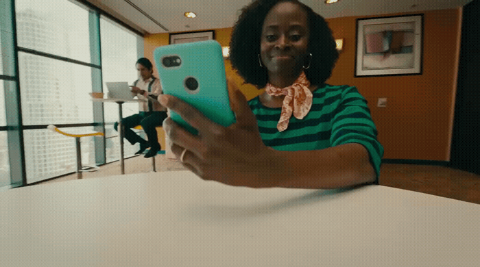 a woman sitting at a table holding a cell phone