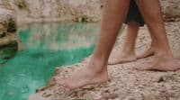 a person standing on a rock next to a body of water