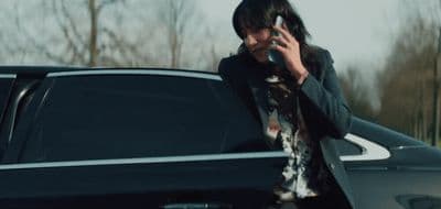 a woman talking on a cell phone next to a car
