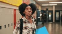 a woman with an afro walking down a hallway