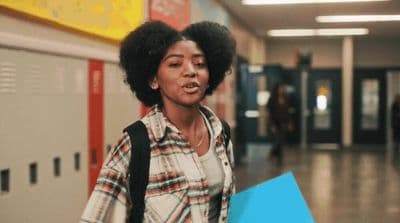a woman with an afro walking down a hallway