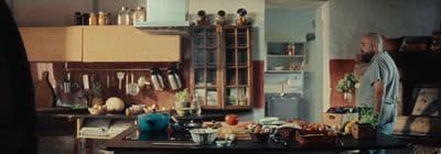 a man standing in a kitchen next to a table