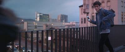 a man standing on a balcony looking at his cell phone