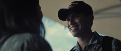a smiling man in a military uniform talking to a woman