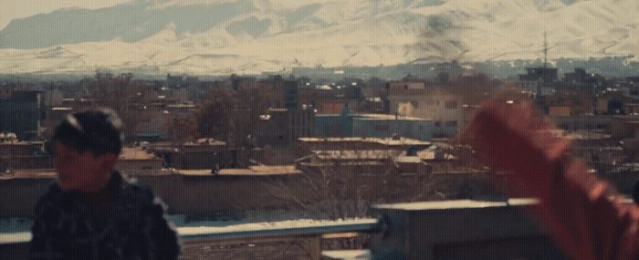 a man standing on top of a building next to a snow covered mountain