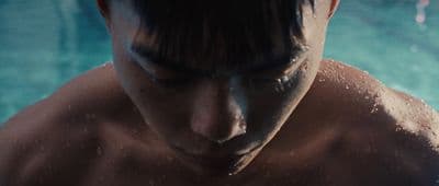 a shirtless man standing in front of a swimming pool