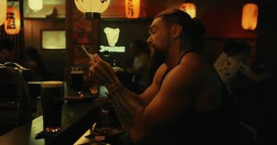 a man sitting at a bar looking at his cell phone