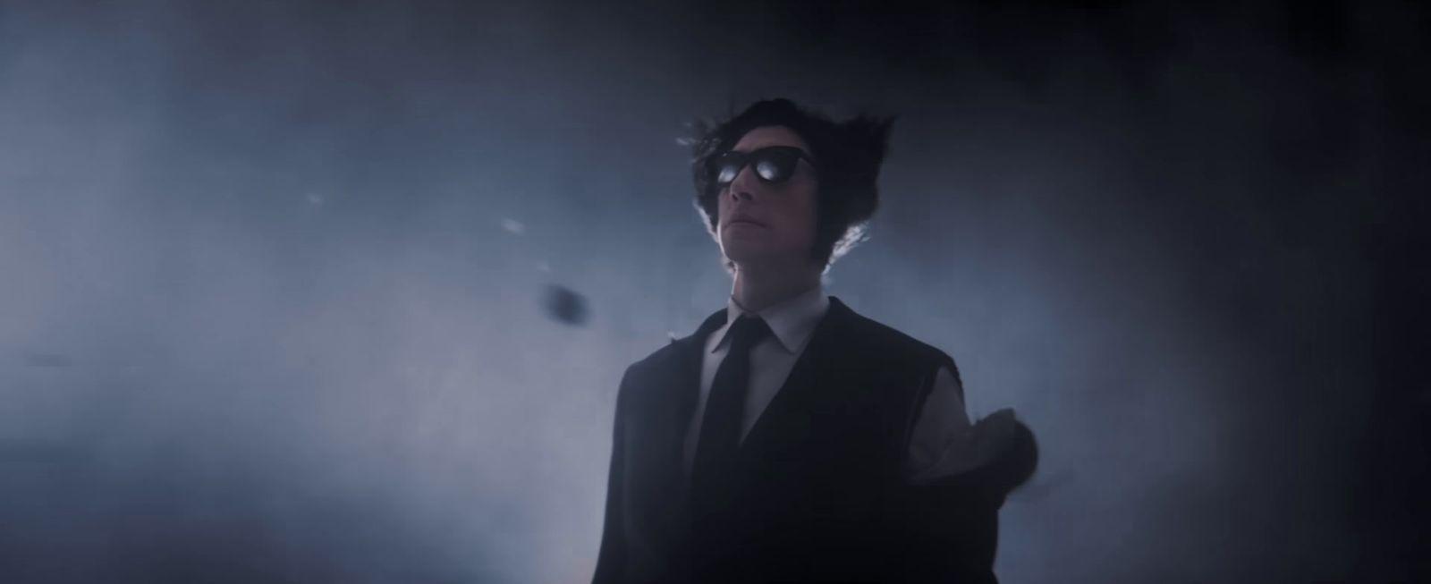a man in a suit and tie standing in a dark room