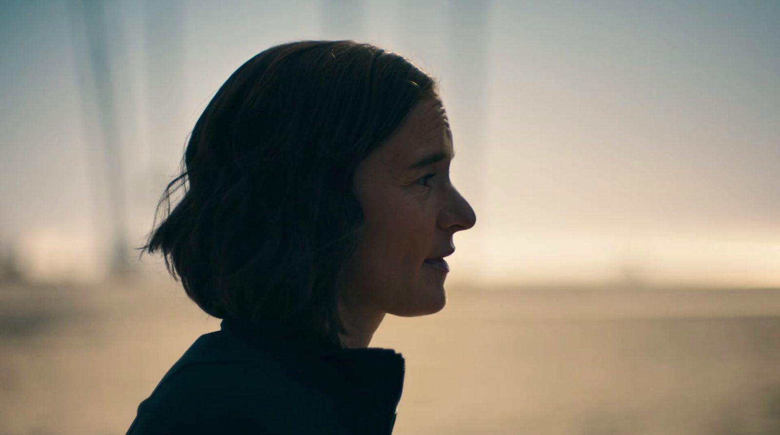 a woman standing in front of a bridge at sunset