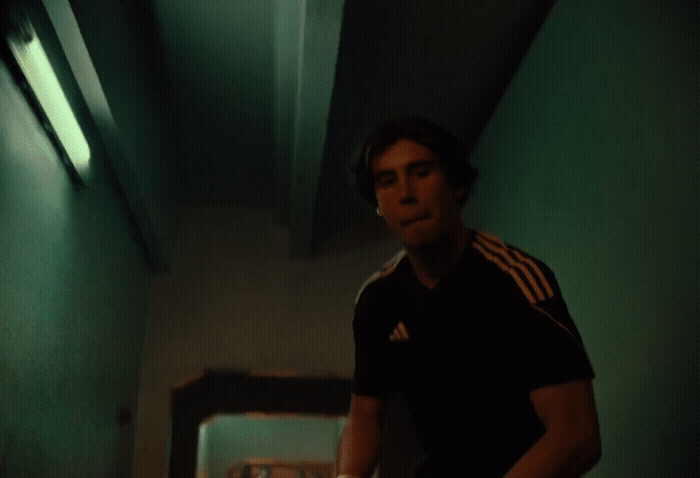 a man standing in a hallway holding a nintendo wii game controller