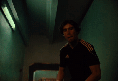 a man standing in a hallway holding a nintendo wii game controller