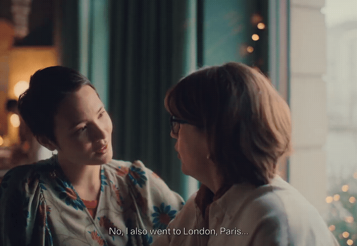 two women standing next to each other in front of a window