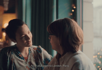 two women standing next to each other in front of a window