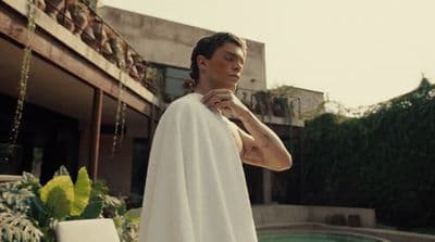 a man in a white towel standing next to a pool
