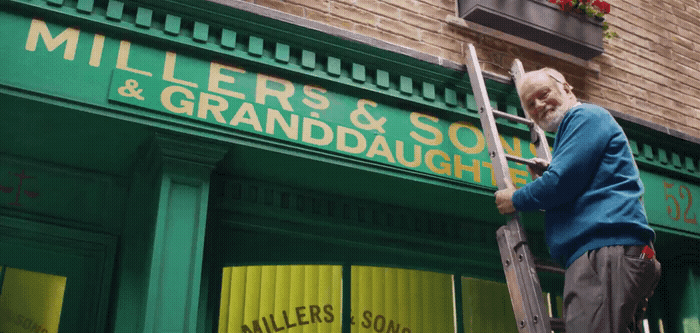 a man standing on a ladder in front of a store