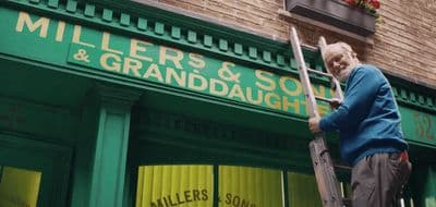 a man standing on a ladder in front of a store