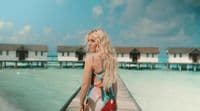 a woman standing on a pier next to a body of water