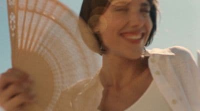 a woman holding a white fan in her right hand