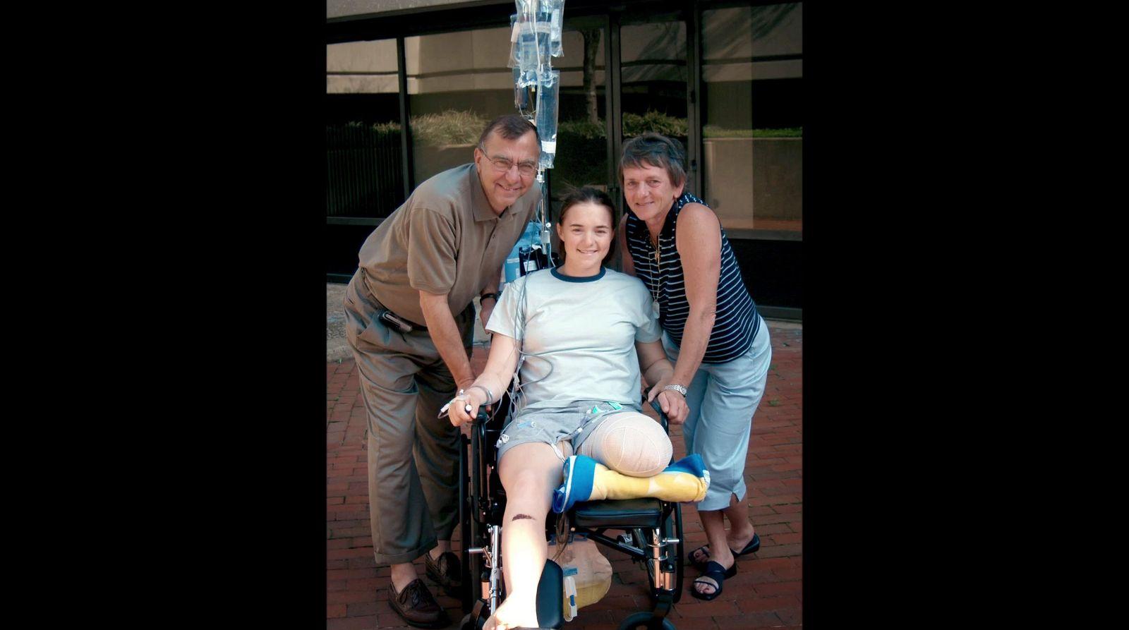 a woman in a wheel chair with two men