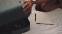 a person laying on a bed with a book and a pen