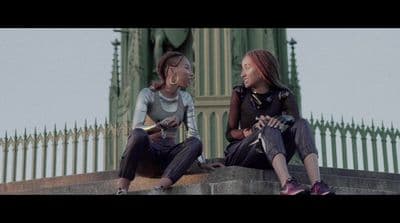 two women sitting on a ledge talking to each other